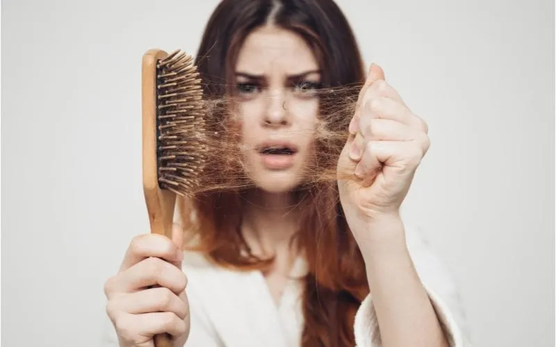Young woman holding a brush and hair for a blog post on what is fine hair