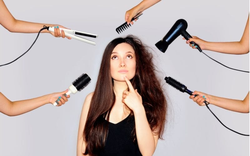 To help illustrate how long a blowout lasts, a woman with frizzy hair on one side and straight long hair on the other and hair tools hovering around her head