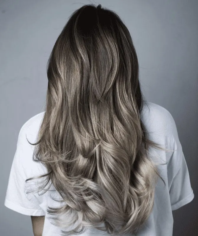 Lady turning away from the camera with multi-hued hair highlights to help answer what is Ombre while she stands in a white shirt
