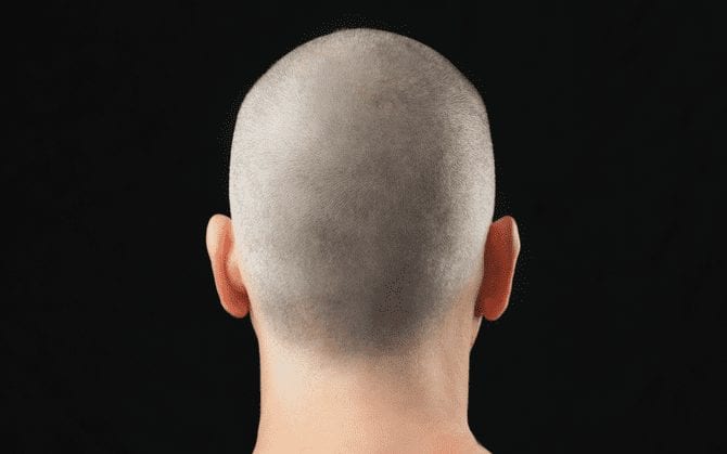 Guy with a zero haircut looks away from the camera and stares at a black background