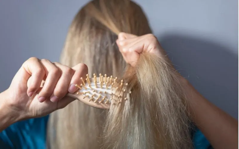 Image of a blonde woman combing her fine hair after using coconut oil