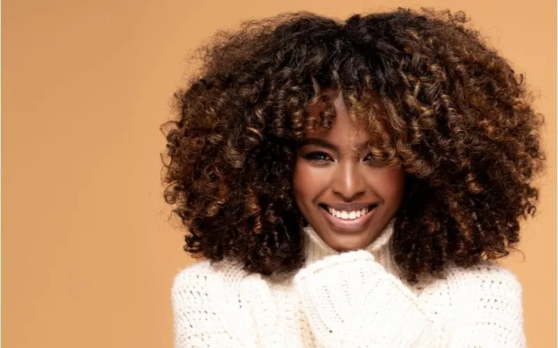 Twist out hairstyle on a beautiful African American woman smiling in a white sweater