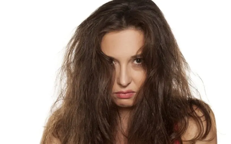 For a piece on the best hair serum, a woman with frizzy hair pouts as she looks at the camera