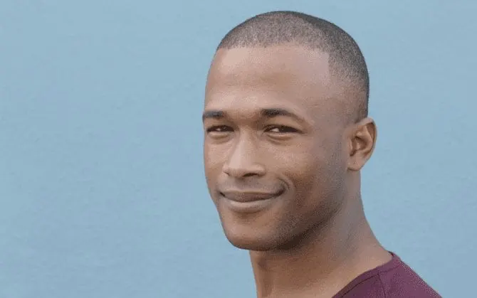 To illustrate the hair clipper sizes and haircut numbers, an Afro-American man grins while looking out of the corner of his eye