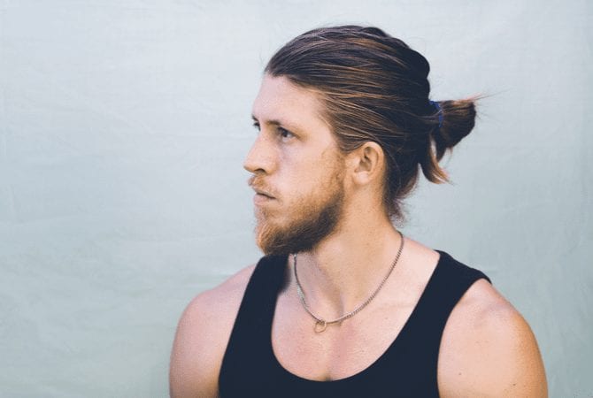 Guy with a basic man bun wearing a black tank top and a chain