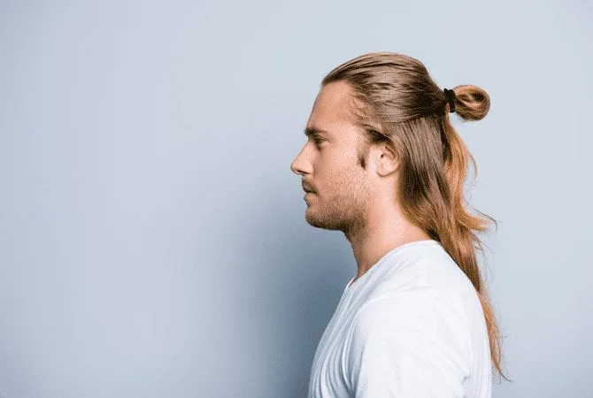 Side profile image of a man in a white shirt for a piece on how to do a man bun