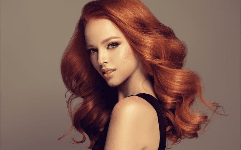 Lady with Voluminous Light Auburn Curls looks to her right in a studio