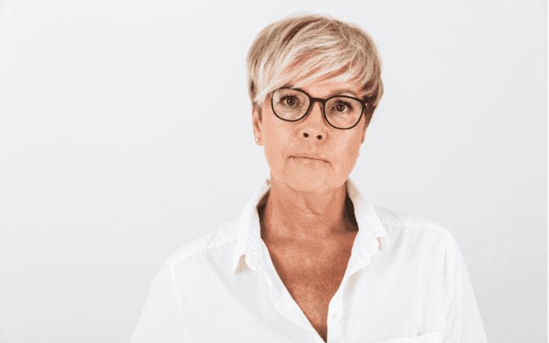 As a featured style for a piece on short haircuts for women over 60, a lady with a dyed haircut in glasses and a white shirt