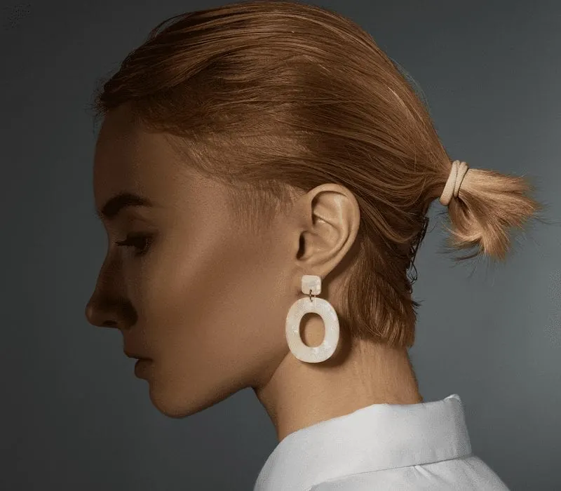 Low Pony on a euro-looking woman with a white button-up and white square earrings