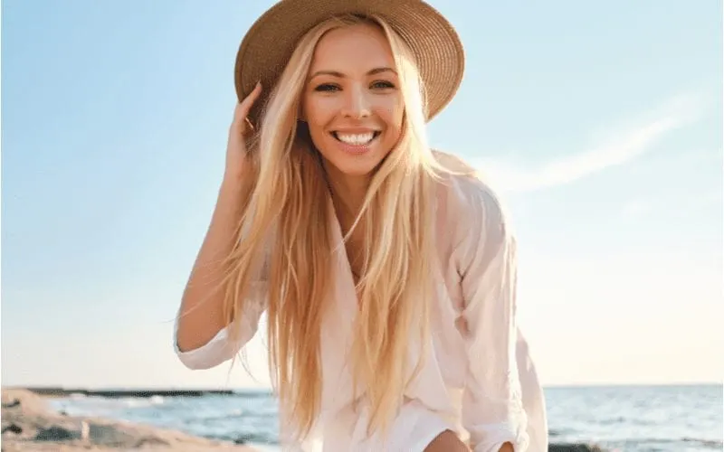 Fine Hair With Long Layers on a woman at a beach in a brown wicker hat