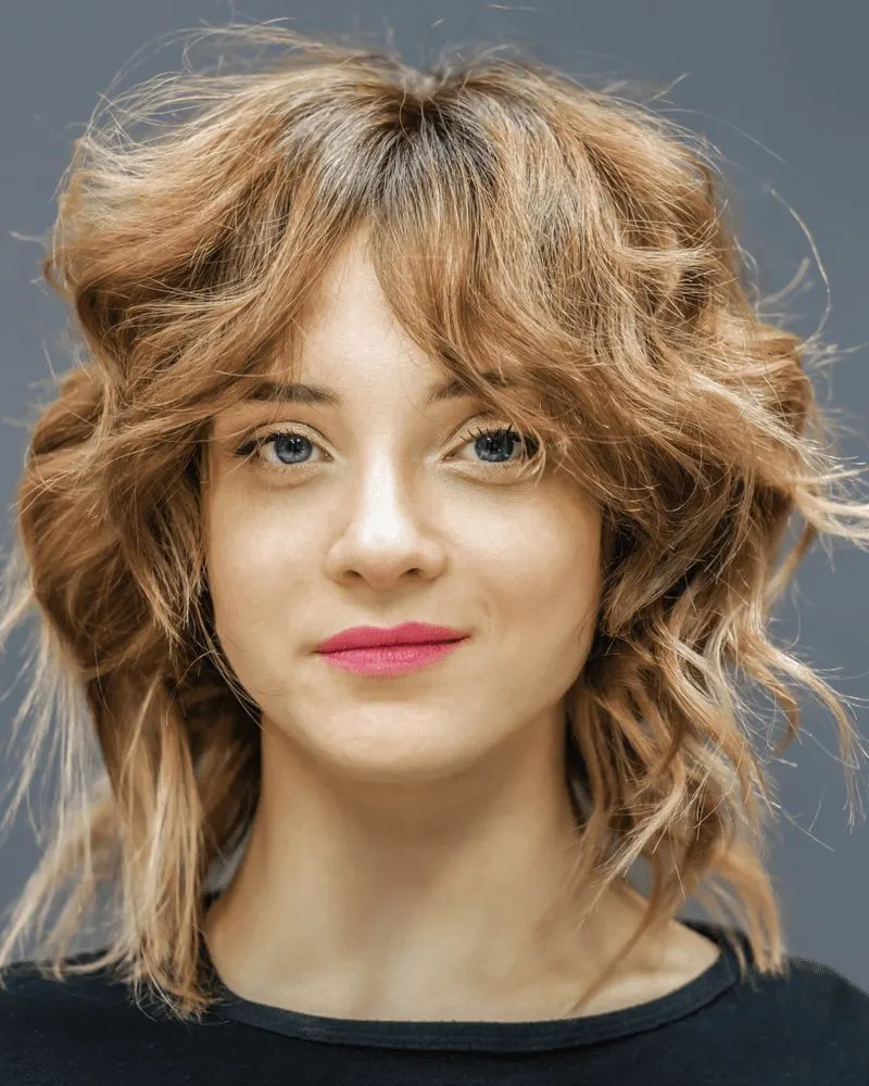Image of a woman with wolf cut hair, a trend on Tiktok smiling looking at the camera