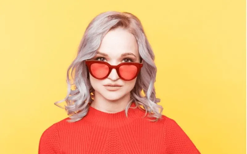 Lilac Platinum Curls on a woman in red glasses and a red shirt in an orange room