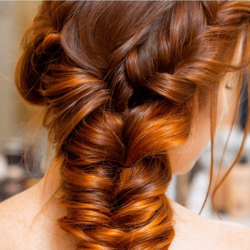 Close-up of a gal with a long red braided hairstyle