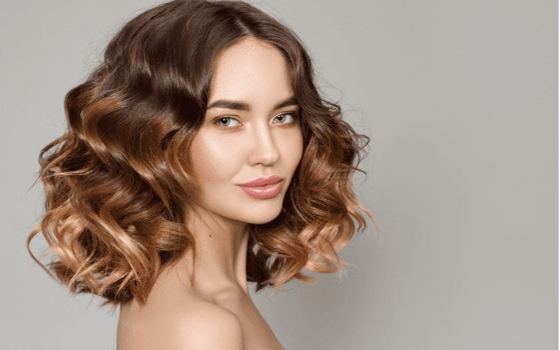 Woman with a curly balayage medium-length haircut looks right