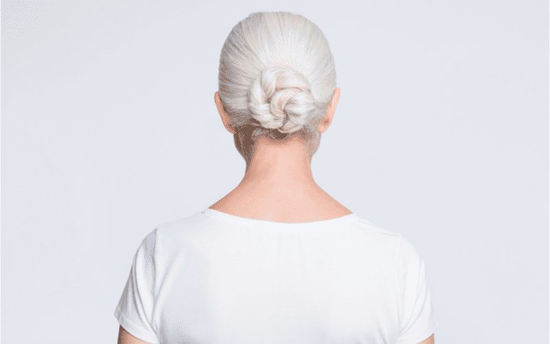 As inspiration for a piece on the best hairstyles for women over 50, a woman wearing a Braided Low Bun cut