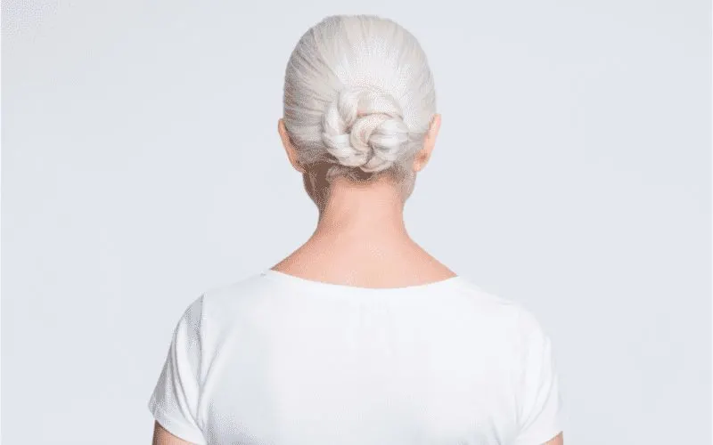 As inspiration for a piece on the best hairstyles for women over 50, a woman wearing a Braided Low Bun cut