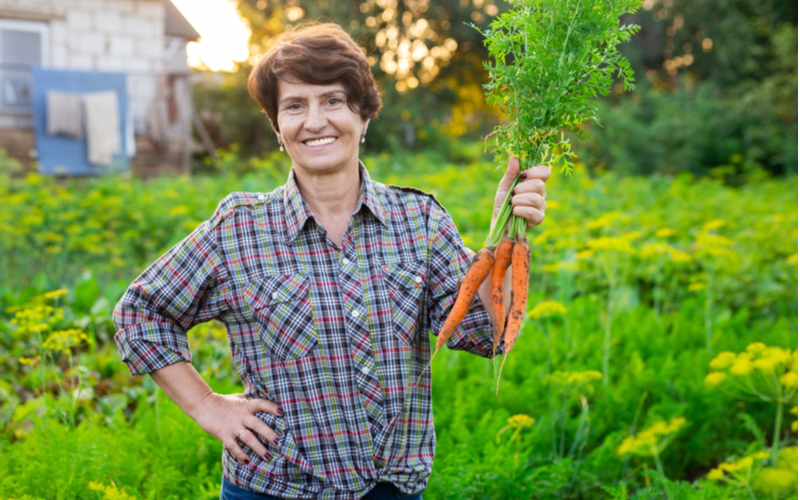Quiff Pixie Cut on a gardener holding carrots standing in front of greenery