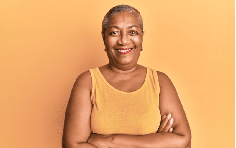 Shaved and Chic black woman crossing her arms and wearing an orange shirt