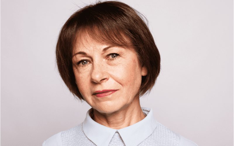 Older woman with a Chin-Length Tucked Bob looks at the camera from the shoulders up without smiling