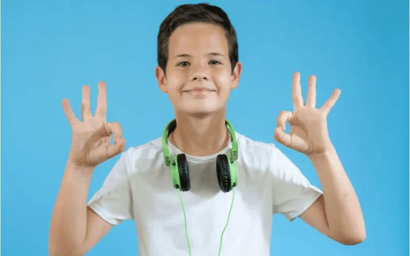 Photo of a boy with a Over and Back Tapered Cut giving two ok signs with his hands
