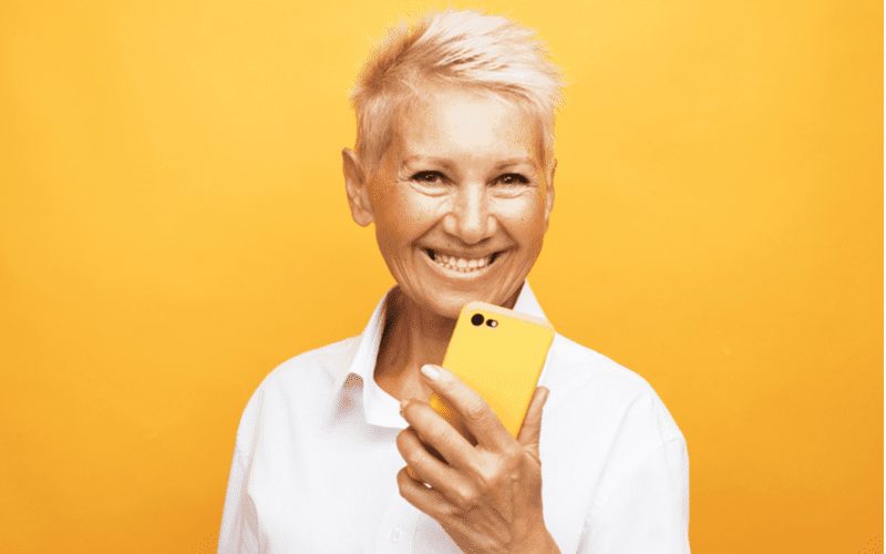 Spiky Side-Swept Pixie on a woman holding an iphone in a yellow case