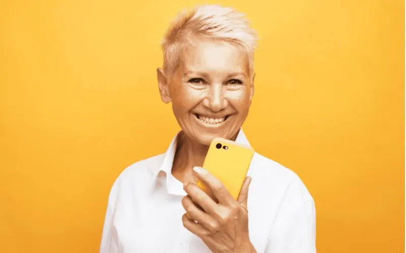 Spiky Side-Swept Pixie on a woman holding an iphone in a yellow case