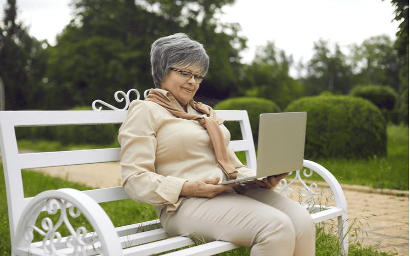 Example of a short haircut for older women on a lady in a buttonup shirt looking at a laptop