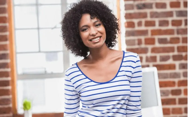 Black woman in a striped shirt has Tapered Shoulder Length Coils hair