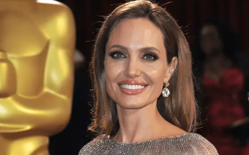 Angelina Jolie, who has a square face, poses in front of the academy award statue with a lob haircut