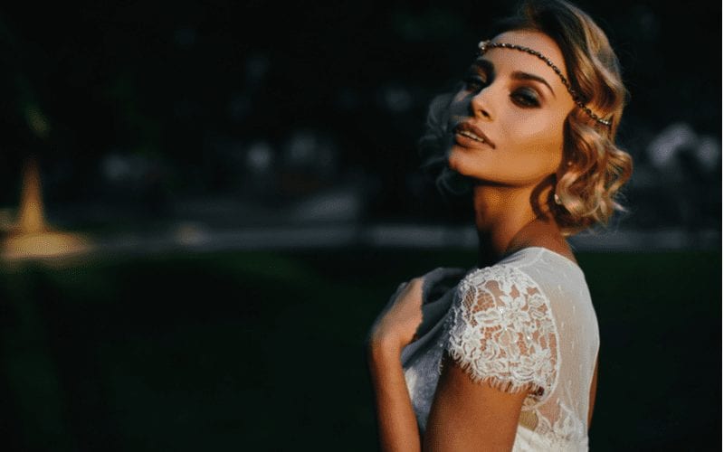 Fair skinned woman wears boho curls with a headband in a white lacey dress