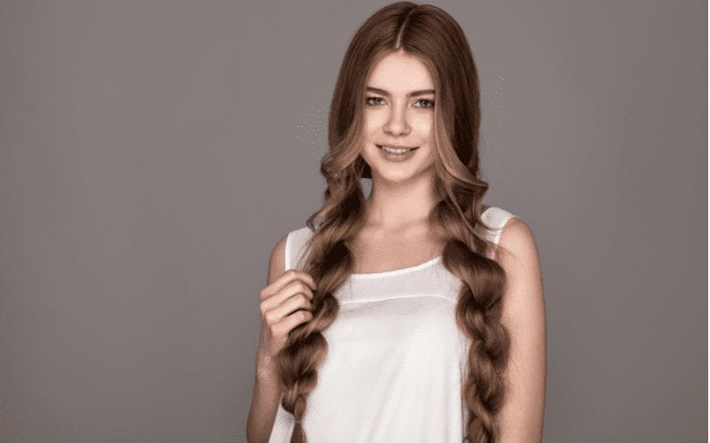 Image of a type of braid featuring a long style on a woman wearing a white shirt