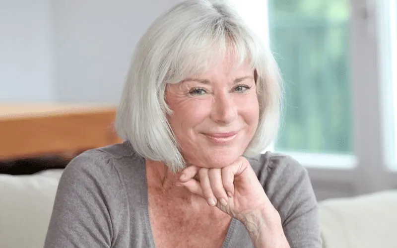 Chin-Length Bob With Full Fringe on a woman holding her fist to her chin for a piece on hairstyles for women over 50
