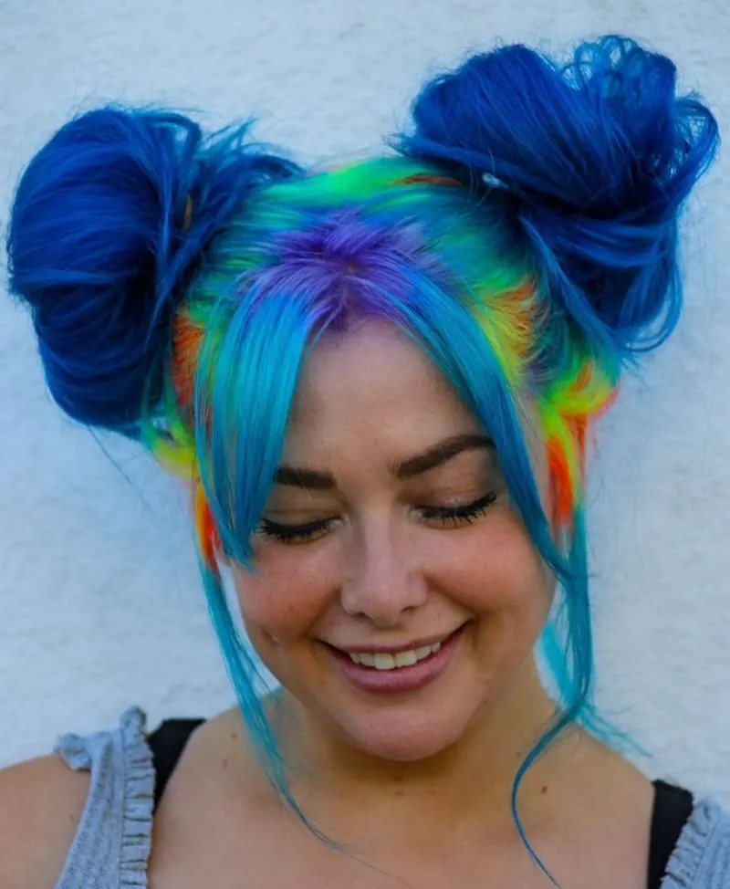 Galaxy colored space buns in yellow, blue, orange, and purple on a freckled woman