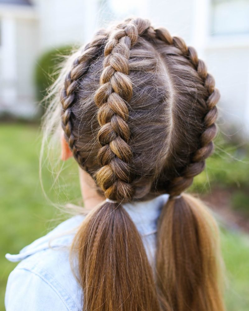 Double milkmaid braid on a gal standing next to a house outside