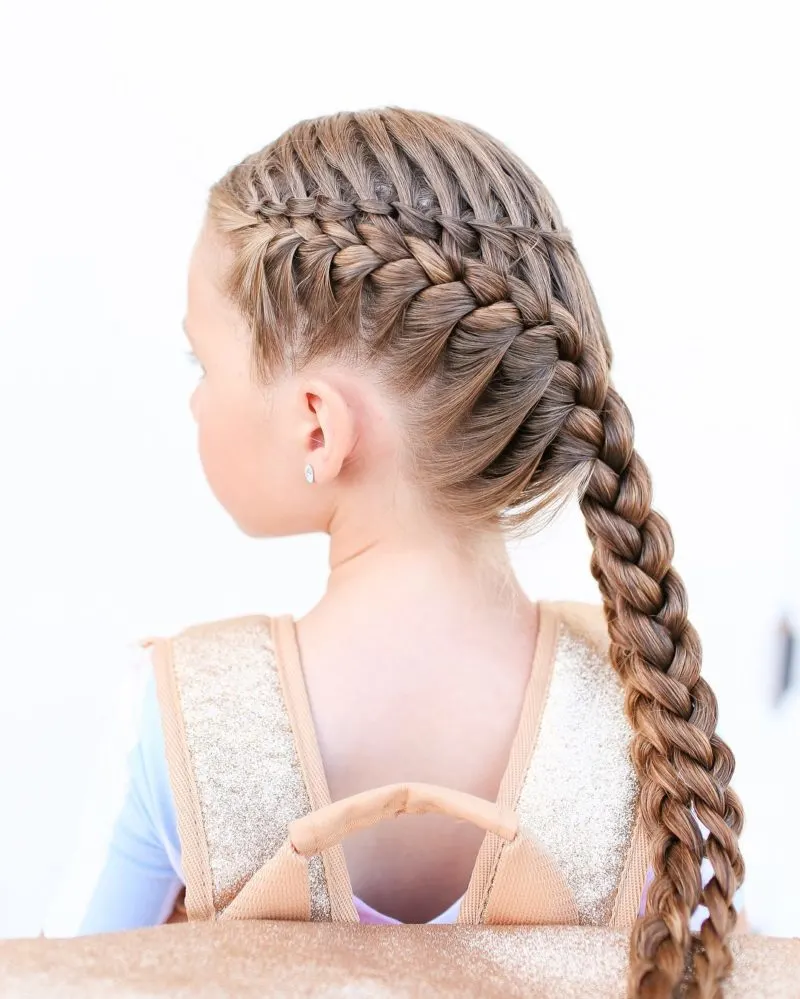 Example of a toddlers braided hairstyle on a gal sitting with a backpack on and looking left