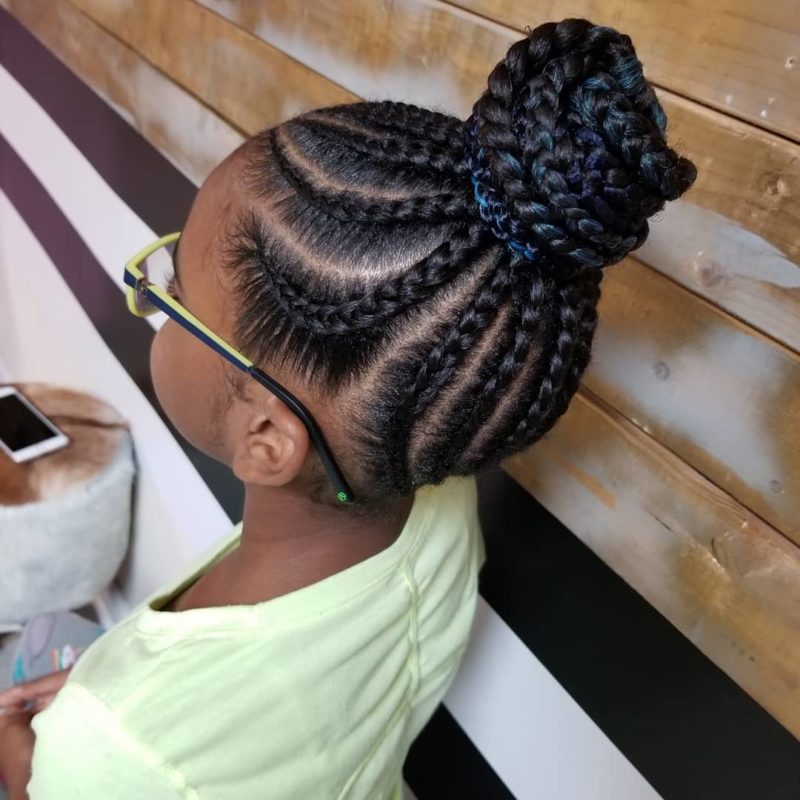 Braided updo on a young afro american woman in a yellow shirt and glasses
