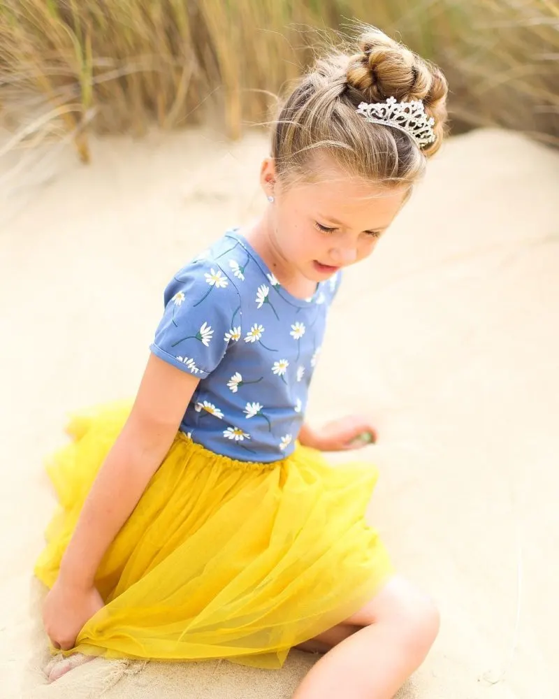 Toddlers braided hairstyle featuring a braided bun being worn by a gal on a beach