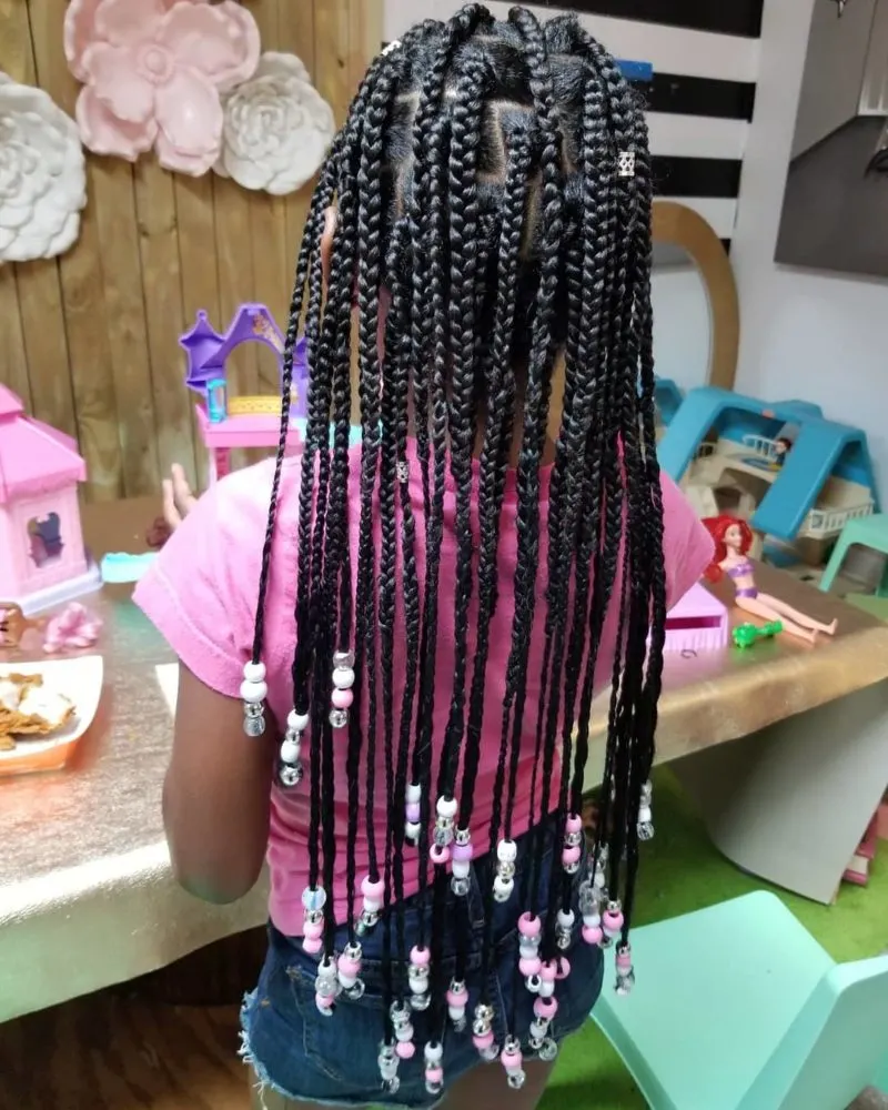 young gal in a pink shirt with a popular braided hairstyle for toddlers
