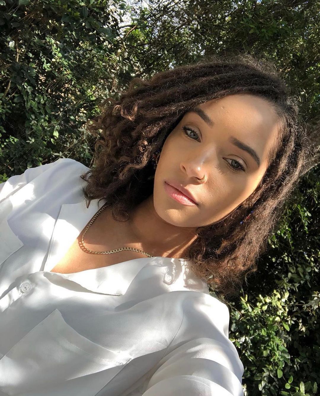 Young woman with semi-freeform dreads in a white button-up