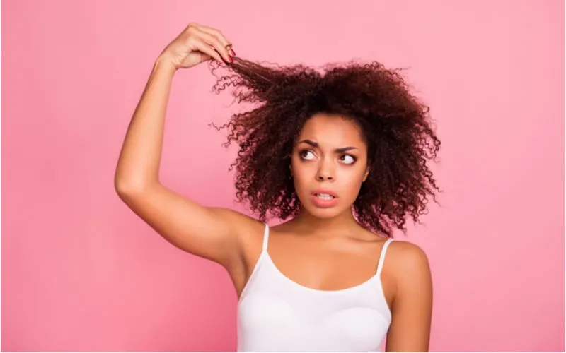 Woman holding her hair and looking up and to the right for a piece on how to dry curly hair