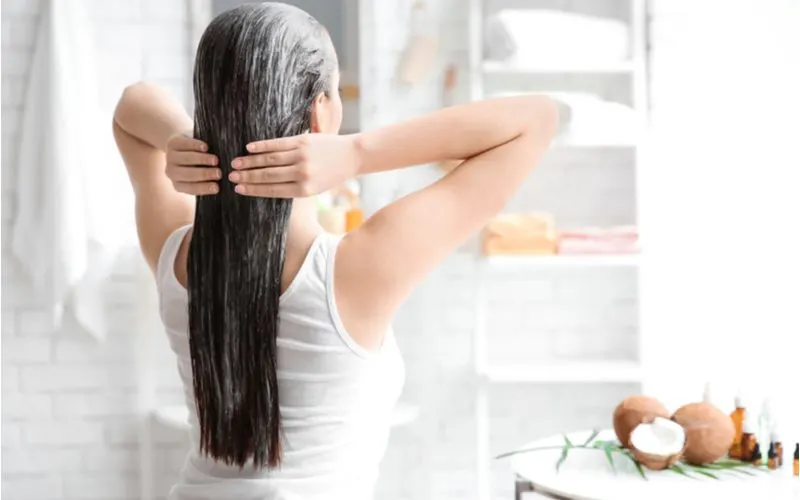 Tall thin brunette woman using a hair mask to get rid of her frizzy hair