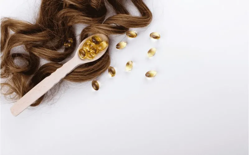 For a piece on how to make hair grow faster, a number of capsules lying on a piece of hair