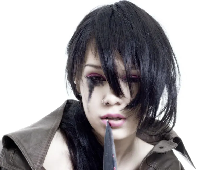 Asymmetrical bob emo haircut on a woman with mascara running down her eyes and putting a knife to her lip