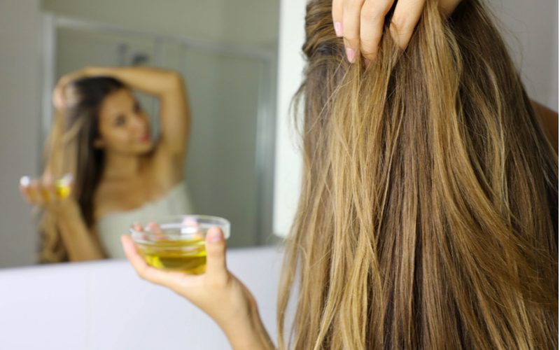 Gal thoa dầu dừa lên tóc để loại bỏ kẹo cao su khi đứng trước gương
