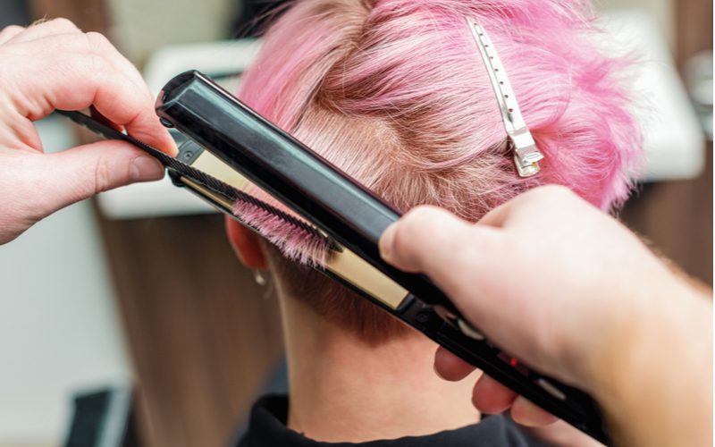Pink haired liberal woman with crazy pink hair curling her really short hair with a flat iron
