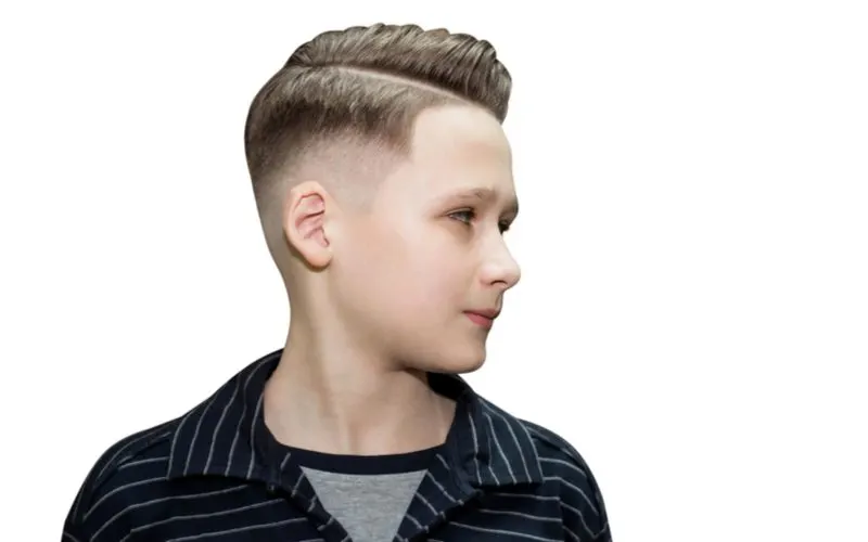 Boy in a black shirt showing off his combed-over undercut fade hairstyle in a studio