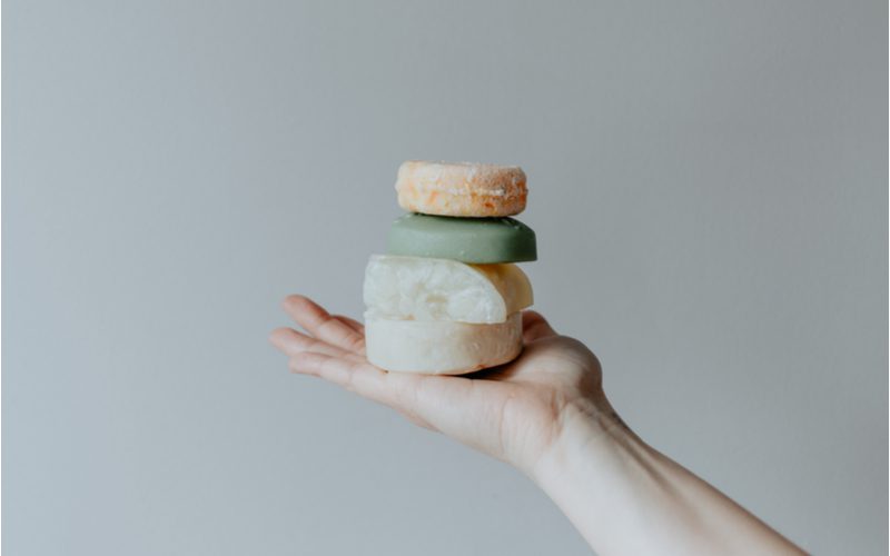 Various types of shampoo bars being held by a hand for a piece on the best shampoo bars