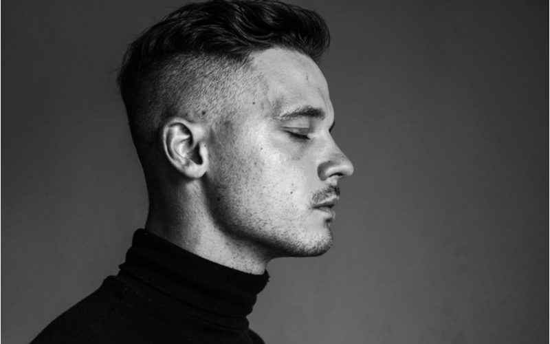 Man with an undercut fade closing his eyes in a black and white photo