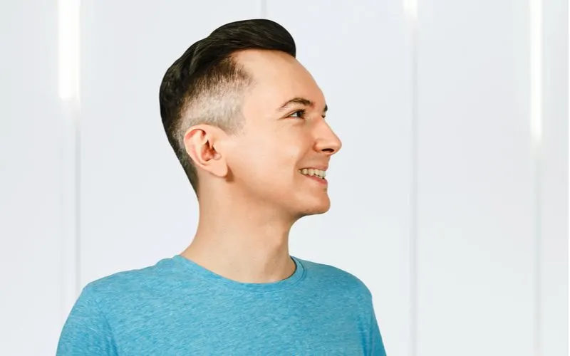 Guy with a textbook undercut fade looks up and to the right while smiling