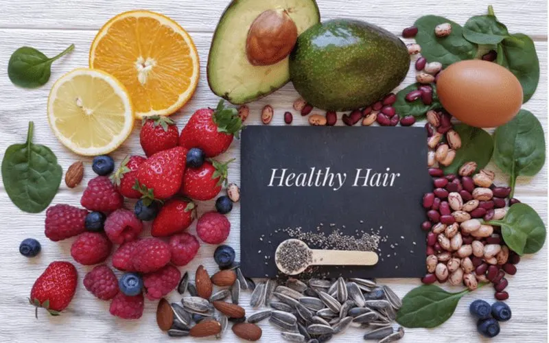 Layflat of nutrient-rich fruits and vegetables with a paper that says healthy hair